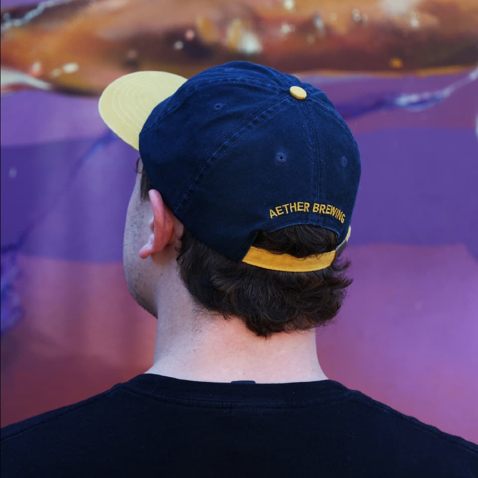Brewery cap by Aether Brewing – yellow on navy, back view